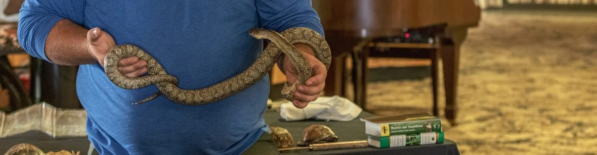 Naturalist presents a live snake during an educational wildlife program inside the lodge, offering guests an up-close learning experience about local animals.