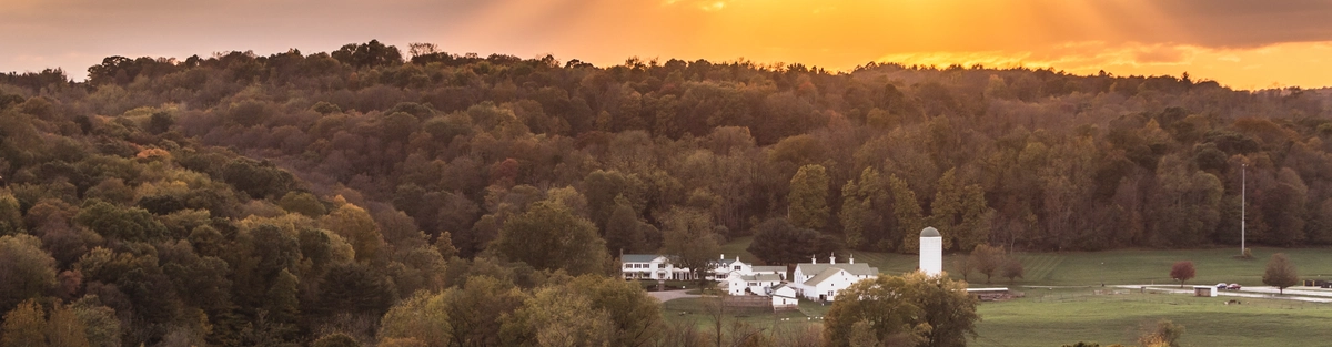 Sunset view overlooking Malabar Farm, with rolling wooded hills glowing in warm evening light beneath a colorful Ohio sky.