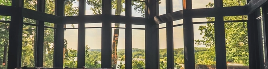 Spacious lodge dining room with floor-to-ceiling windows, offering scenic forest views and a bright, inviting atmosphere for guests to enjoy a meal.